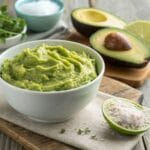 Fresh 4 ingredient guacamole recipe served with lime and avocado on a rustic wooden table