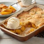 Golden peach cobbler with cake mix served warm with a scoop of vanilla ice cream