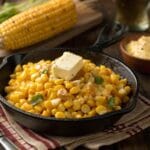 Rich and buttery Southern fried corn recipe in a cast iron skillet, garnished with fresh parsley